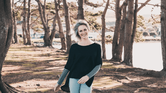 Photo of Sara-Jane Austen, Director and Creative at Designerbloom Graphic Design standing in a forest.