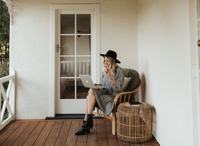 Picture of Nicole sitting outside with a drink in hand and her laptop open on her lap