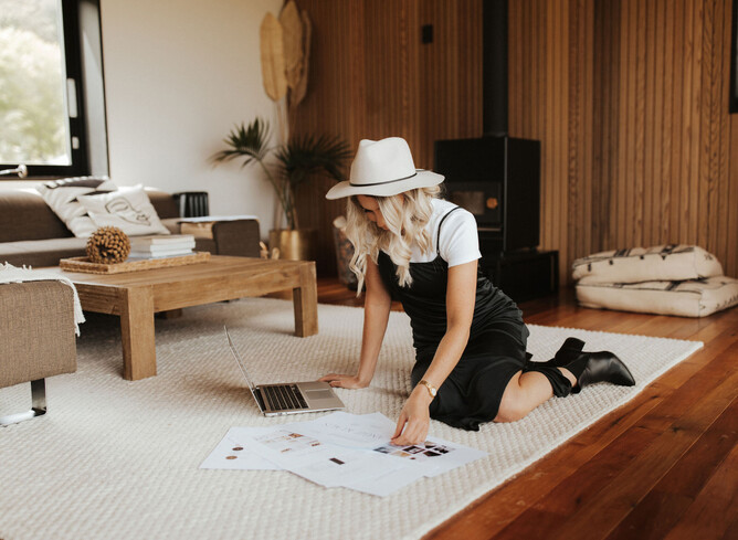 Picture of Nicole on the floor looking at her designs with her laptop