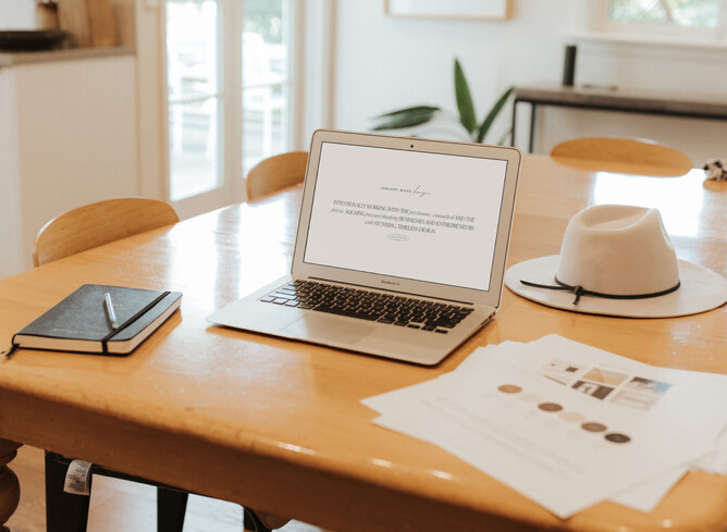 Picture of Nicole's laptop on a table with design pages printed off around